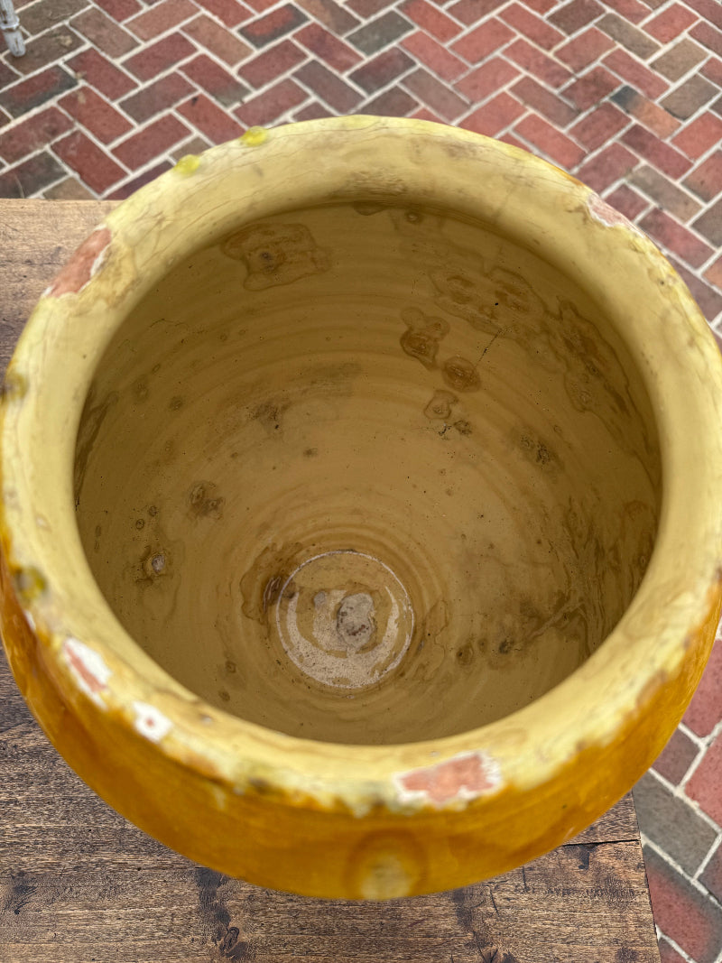 Antique French Yellow ceramic pot with a textured surface on a brick and wooden floor background