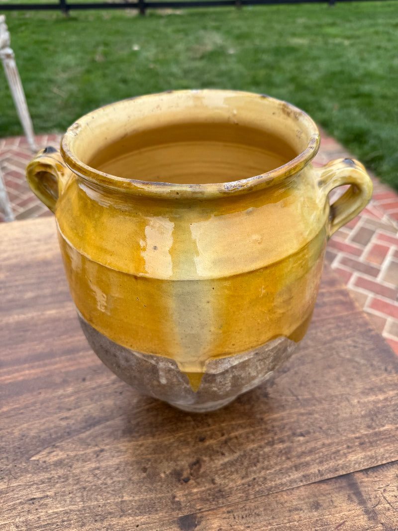 Terra Cotta Glazed Antique French confit on a wooden surface with a blurred outdoor background