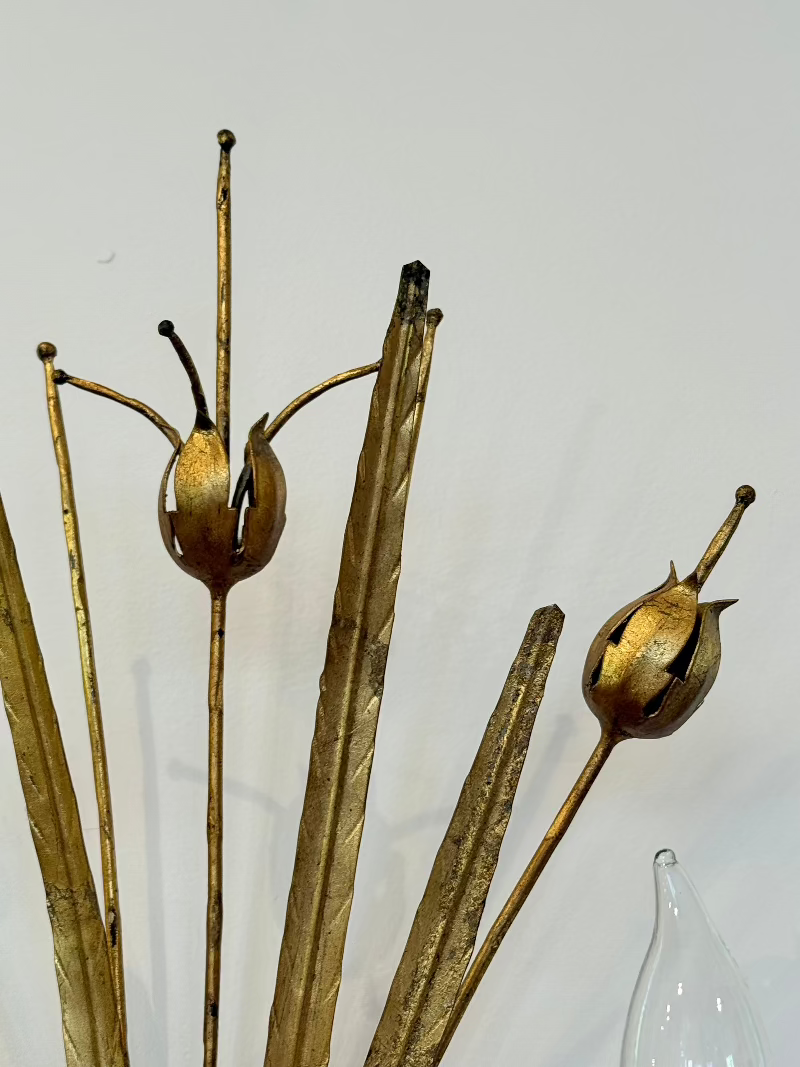 Decorative metal plant with gold and bronze tones against a plain background