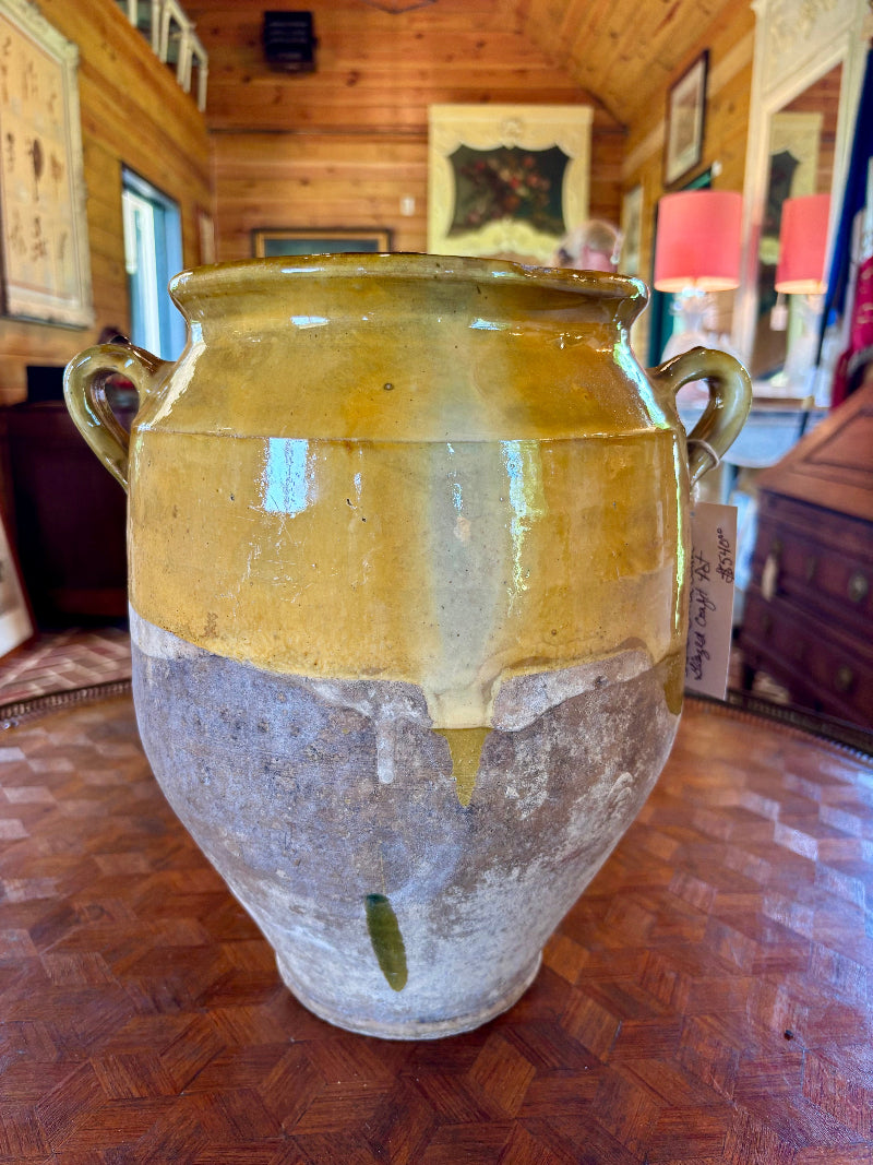 Large ceramic CONFIT 19th century French jar with a yellowish-brown top and gray base on a wooden floor.