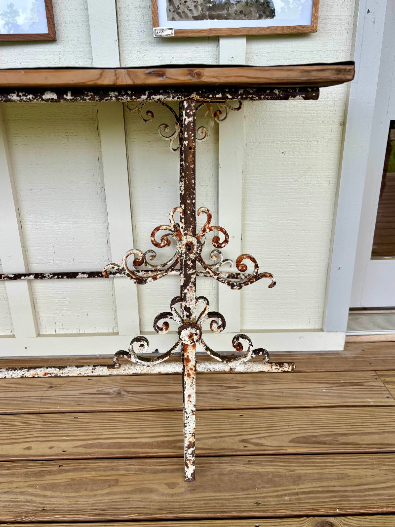 Rustic metal potting table with decorative scroll design on legs