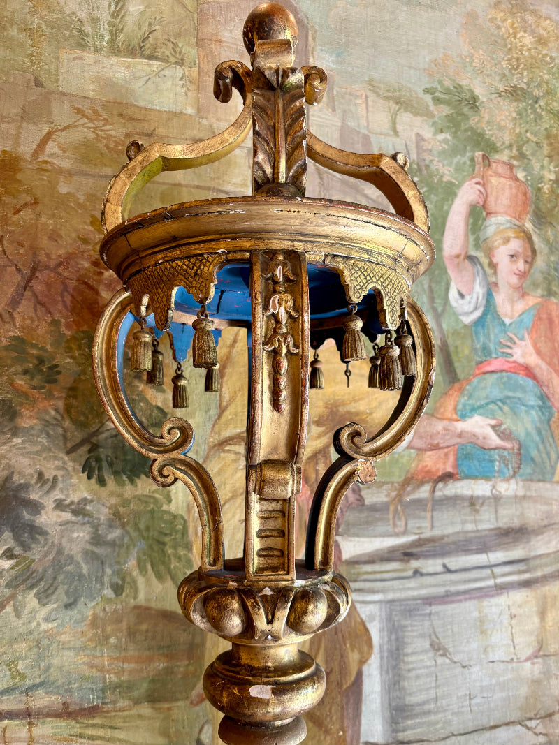 Decorative gold lantern with intricate designs against a mural background