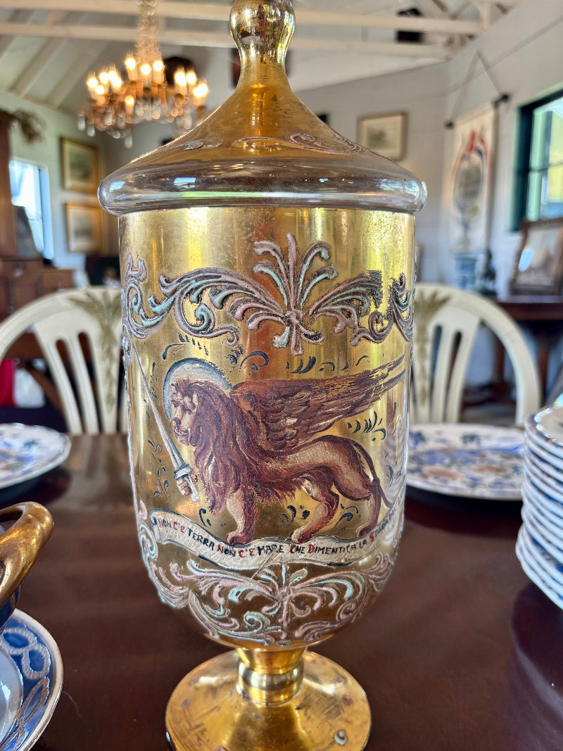 Decorative antique venetian urn with gold accents and intricate designs on a table.