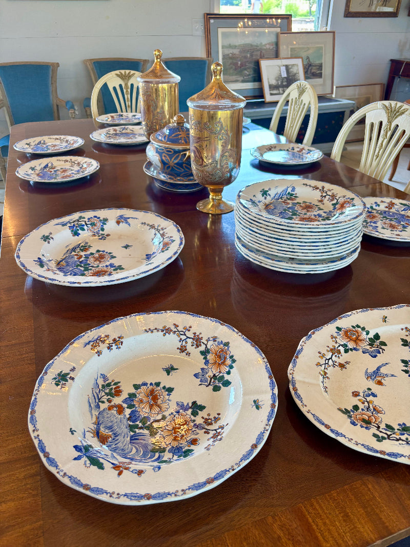 Set of FRENCH Gien plates on a wooden table with a dining room setting in the background.