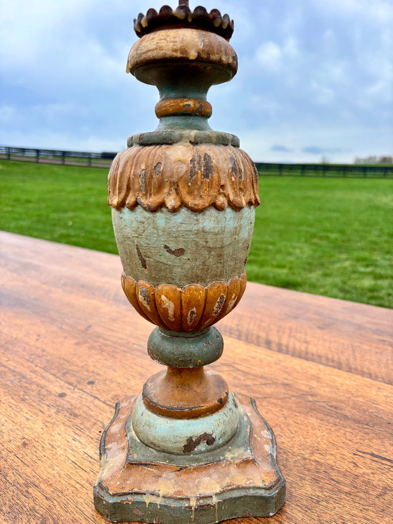 Decorative Italian candlestick with a rustic patina on a wooden surface with a grassy field in the background