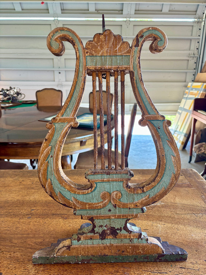 Antique Italian  lyre-shaped object on a wooden surface with a blurred indoor background